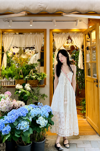 Woman in a white dress standing in front of a flower shop entrance.