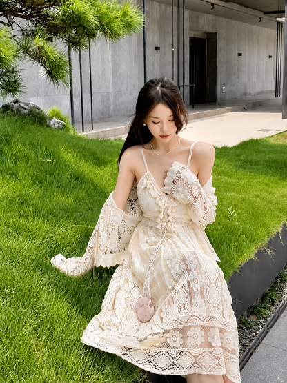 Woman in a white lace dress standing on grass with a modern building in the background