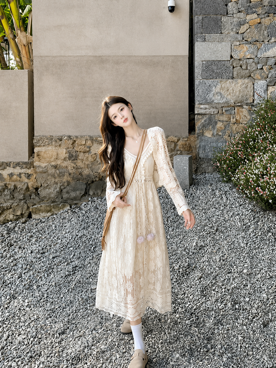 Woman in a white dress standing outdoors near a stone wall.