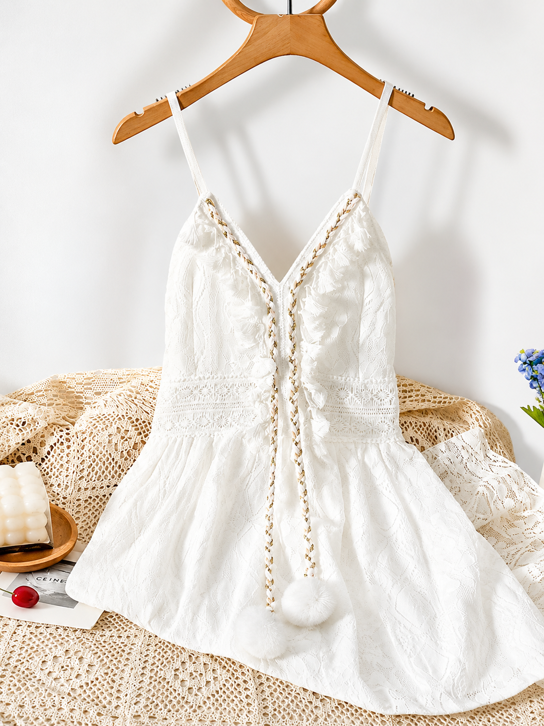White lace dress on a wooden hanger with a textured surface and flowers in the background